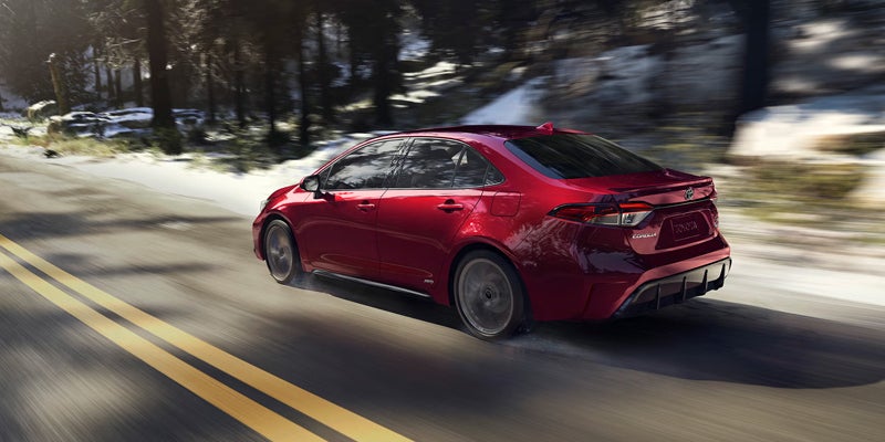 2027 Toyota Corolla Hybrid driving on a snow-lined mountain road