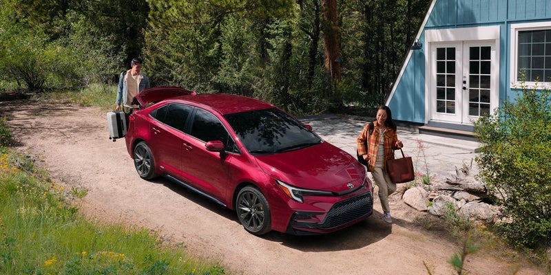 2027 Toyota Corolla parked at a mountain cabin with open trunk for luggage